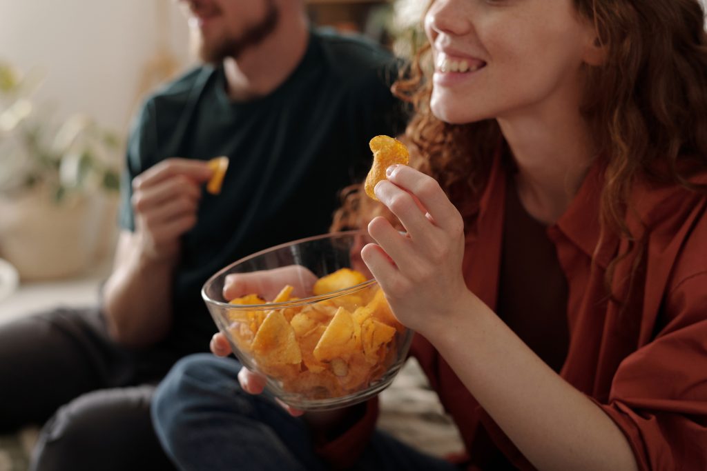 Mujer sonriente sosteniendo un bowl de papas fritas mientras comparte con otra persona